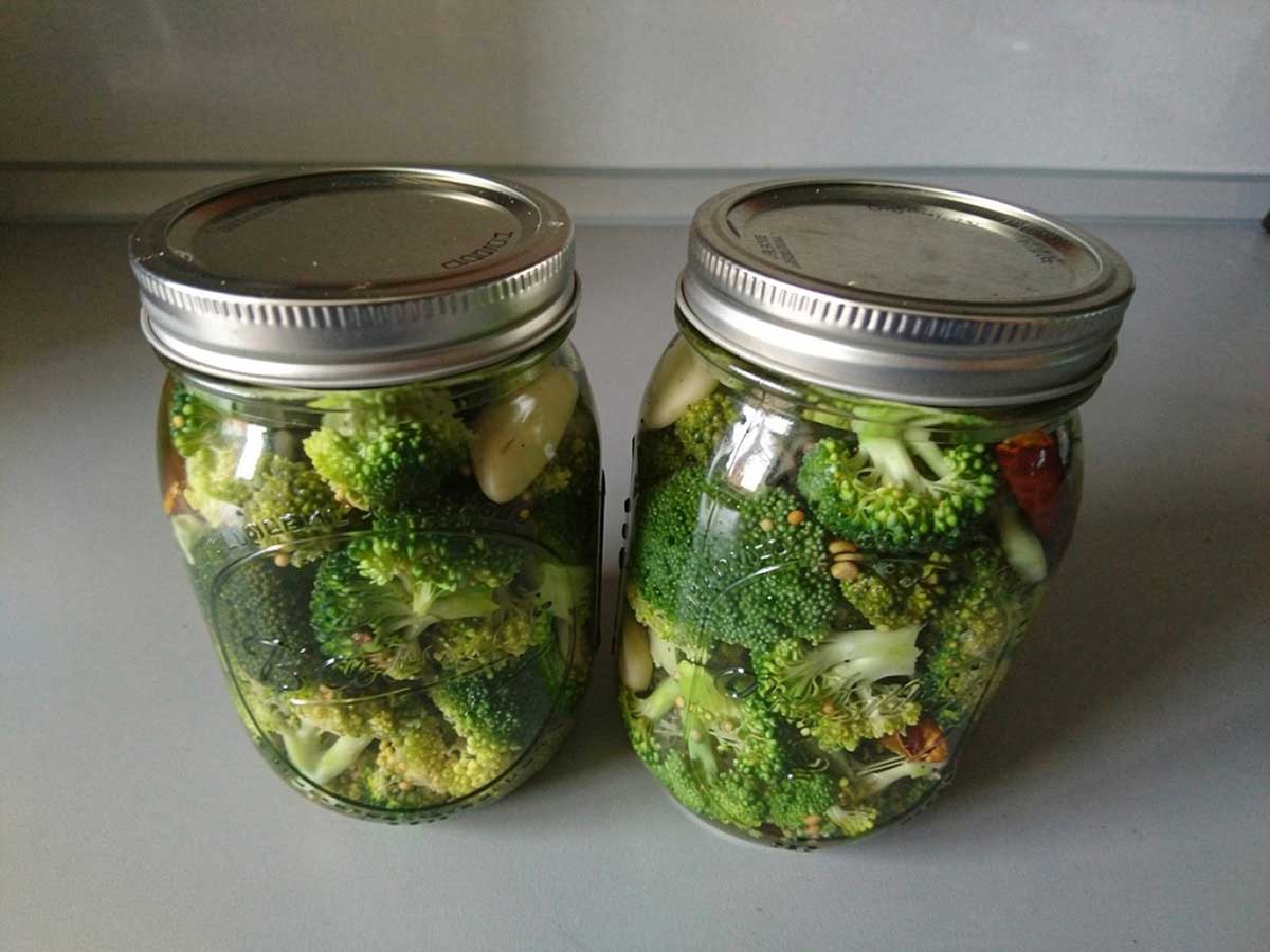 2 inmaakpotten met ingemaakte en geweckte broccoli.