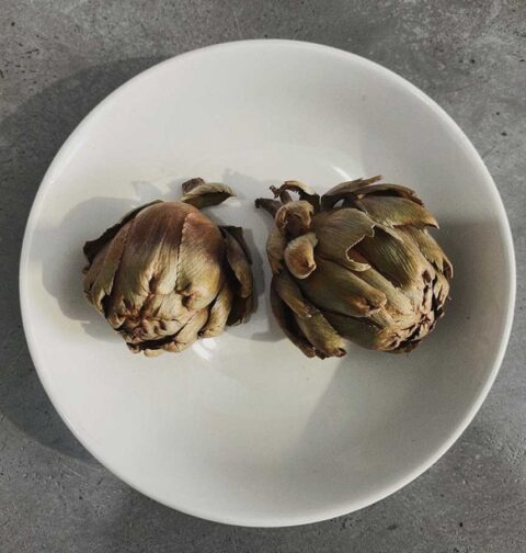 2 gedroogde hele artisjokken in een wit schaaltje.
