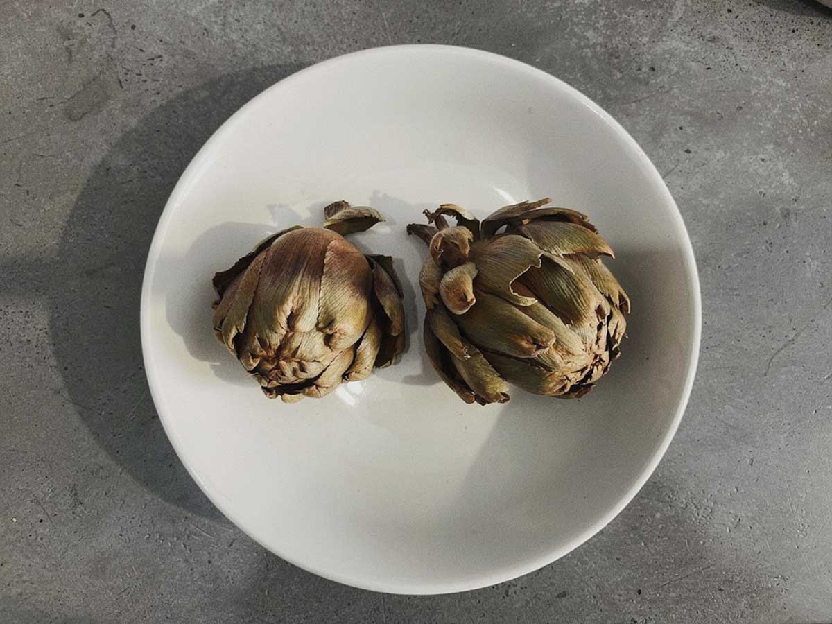 2 gedroogde hele artisjokken in een wit schaaltje.