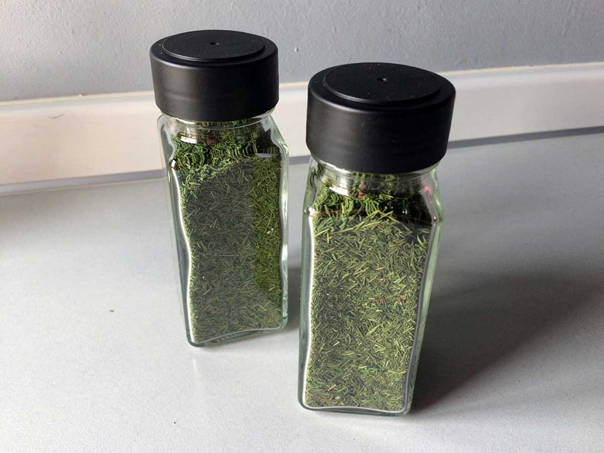 2 kruidenpotjes met gedroogde en verkruimelde dille.