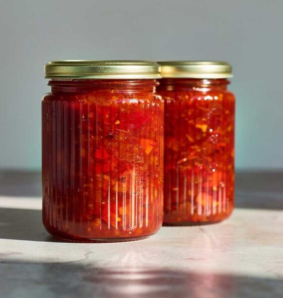 2 grote jampotten met daarin zelfgemaakte paprikachutney van rode paprika's.