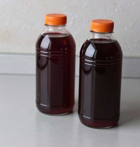 2 plastic flessen met daarin zelfgemaakt vlierbessensap.
