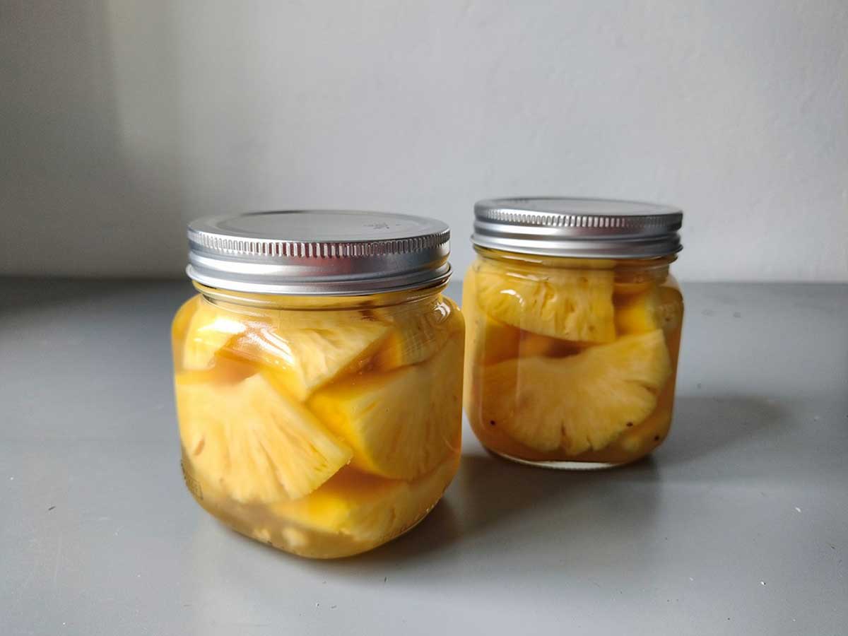 2 inmaakpotten met ingemaakt ananas op een suikersiroop.