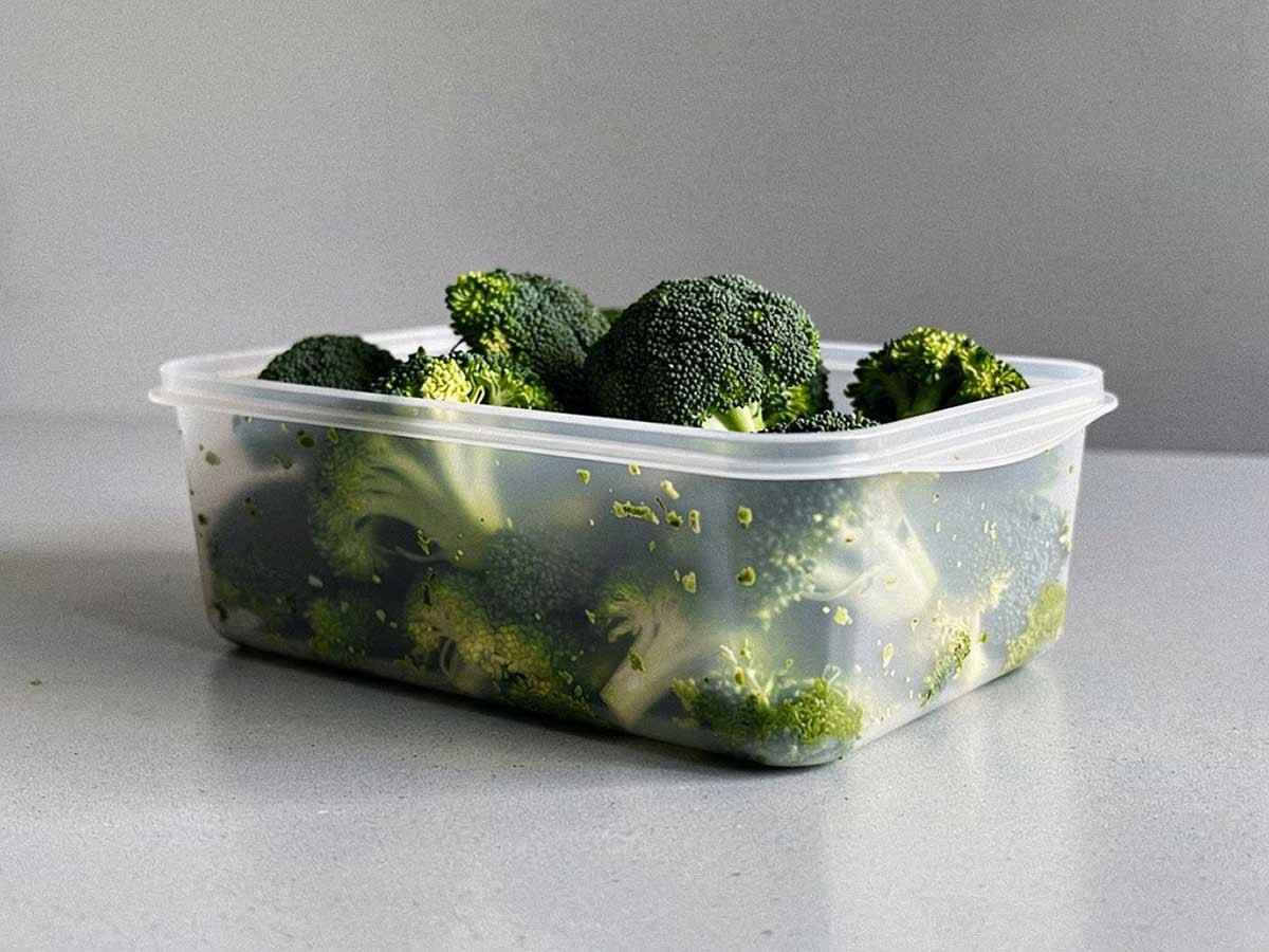 Een diepvriesbakje met daarin geblancheerde roosjes broccoli.