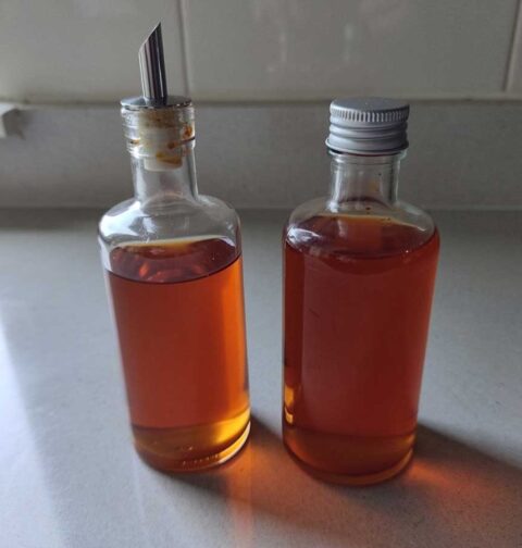 2 flesjes met chiliolie, waarvan er 1 met schenktuit.