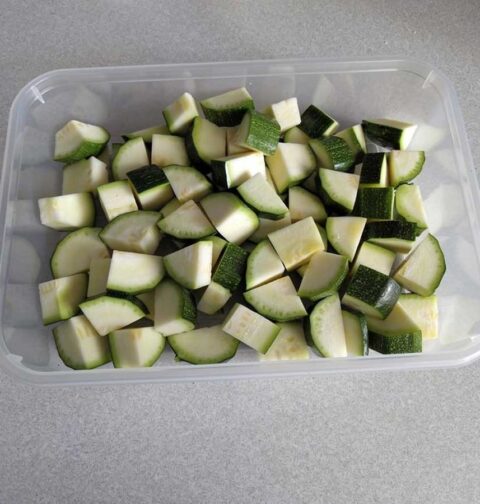 Een diepvriesbak vol met stukjes courgette, klaar om in te vriezen.