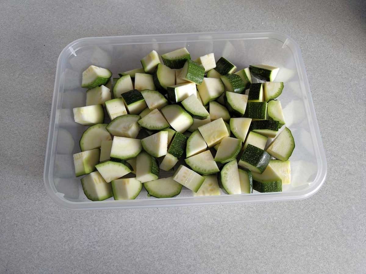 Een diepvriesbak vol met stukjes courgette, klaar om in te vriezen.