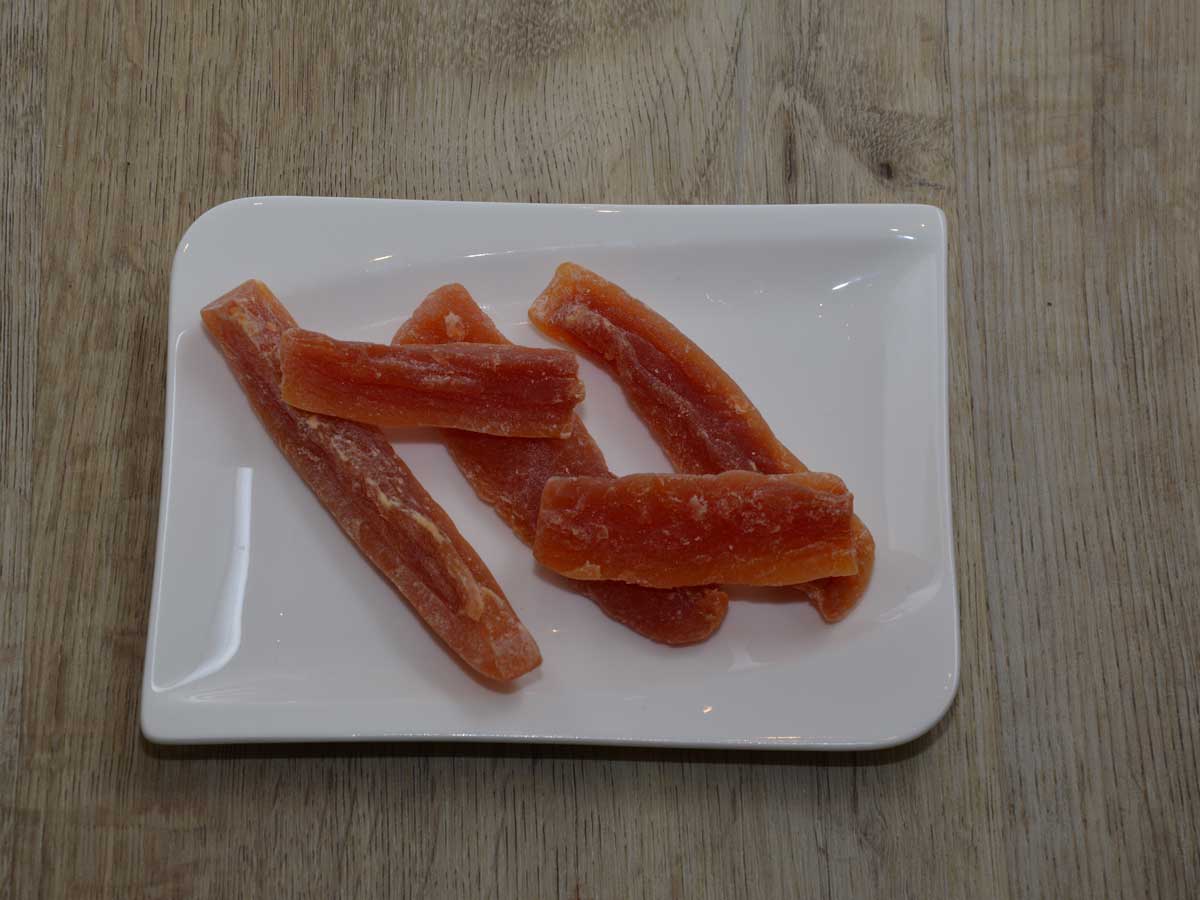 5 stukjes gekonfitje papaja liggen op een wit plat schaaltje.