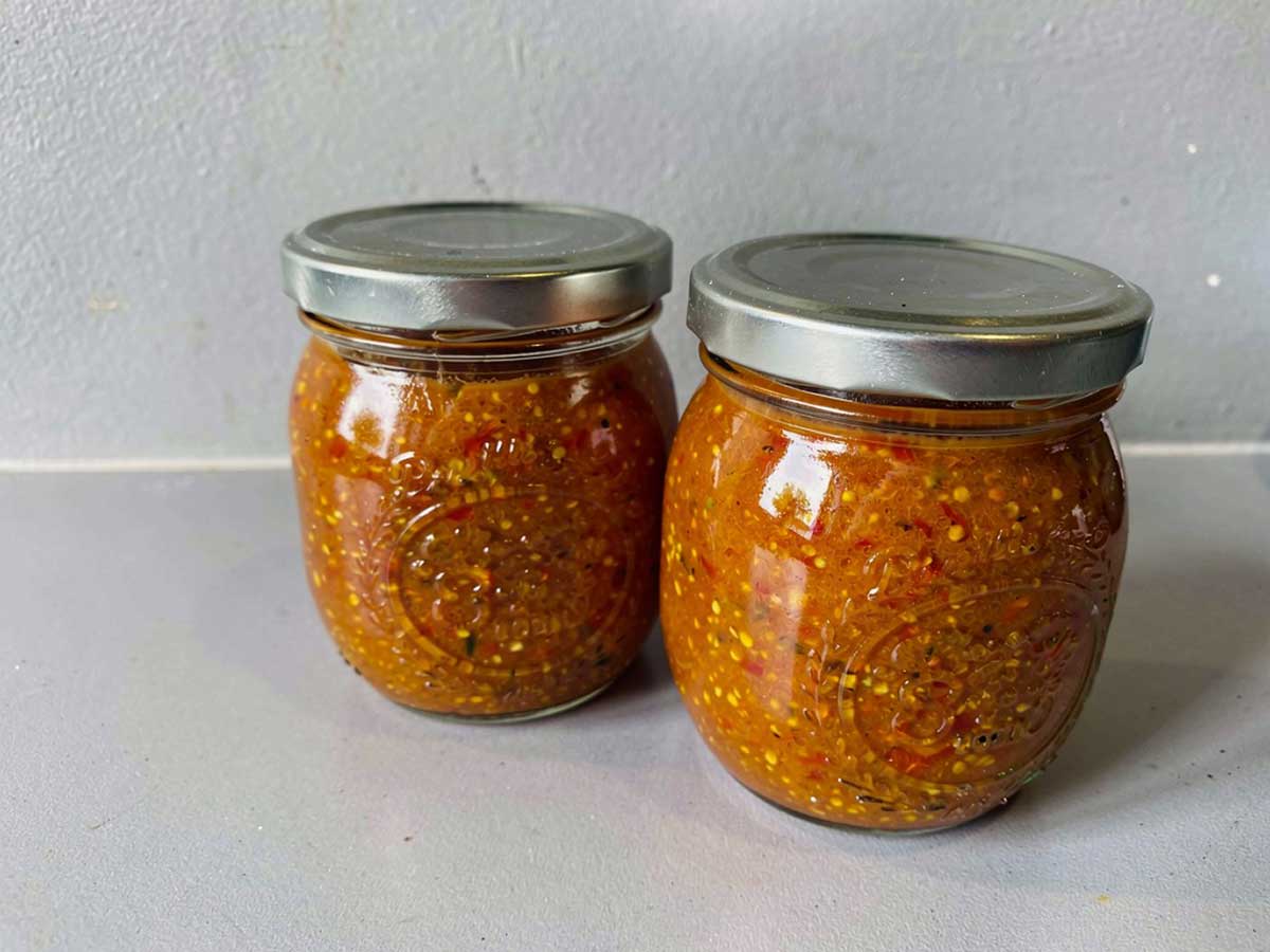 2 grote jampotten met gele tomaat-chili-chutney.