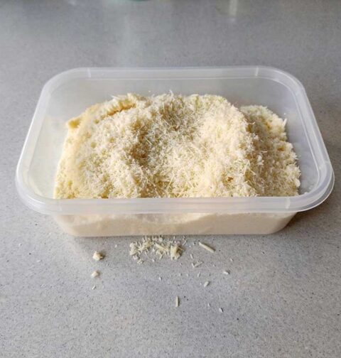 Een diepvriesbakje met geraspte Parmezaanse kaas om in te vriezen.