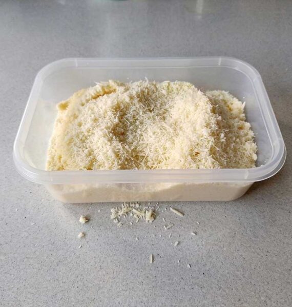 Een diepvriesbakje met geraspte Parmezaanse kaas om in te vriezen.