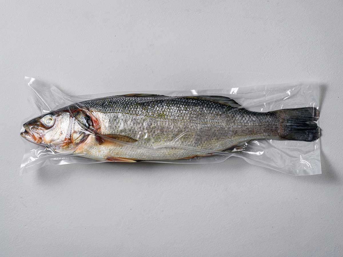 Een in vershoudfolie ingewikkelde zeebaars, die straks in een diepvrieszak kan worden ingevroren.