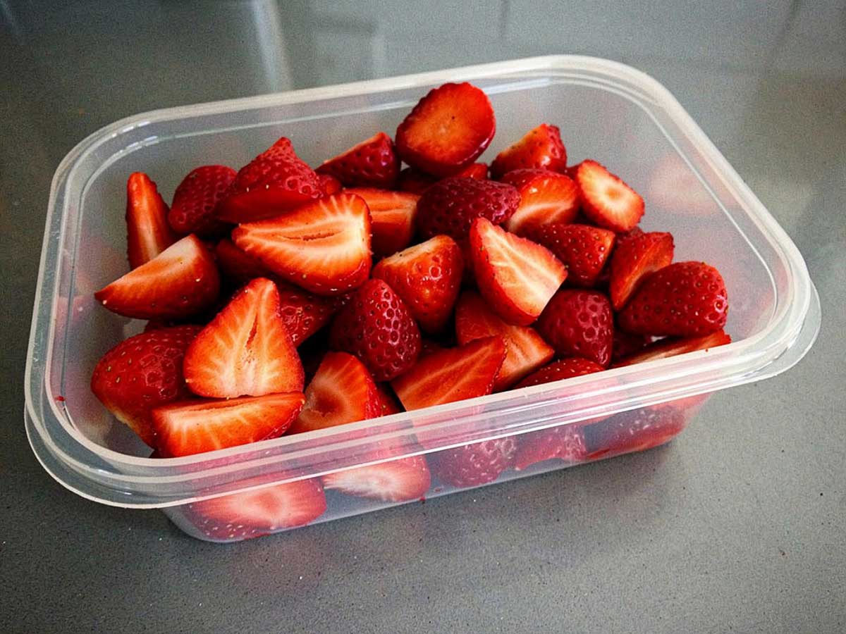 Een diepvriesbakje met gehalveerde aardbeien, om in te vriezen.