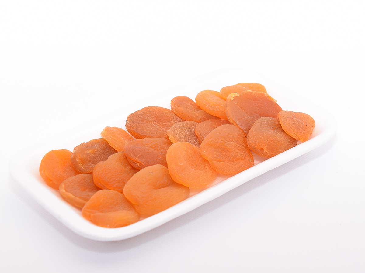 Gedroogde abrikozen op een wit langwerpig schaaltje.