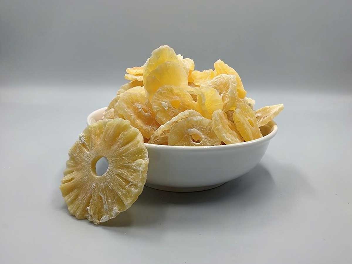 Een schaaltje met schijven gedrogode ananas.