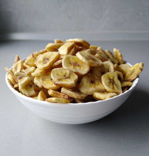 Een wit schaaltje met daarin zelfgemaakte bananenchips, oftewel gedroogde banaan.