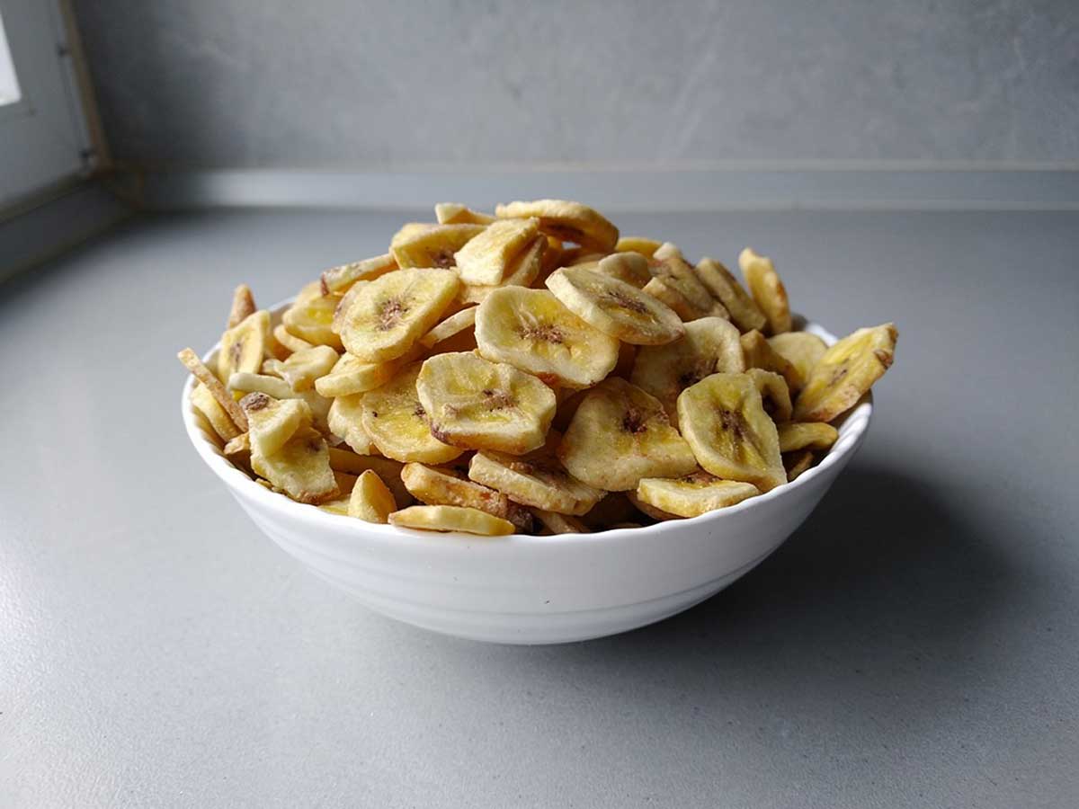 Een wit schaaltje met daarin zelfgemaakte bananenchips, oftewel gedroogde banaan.