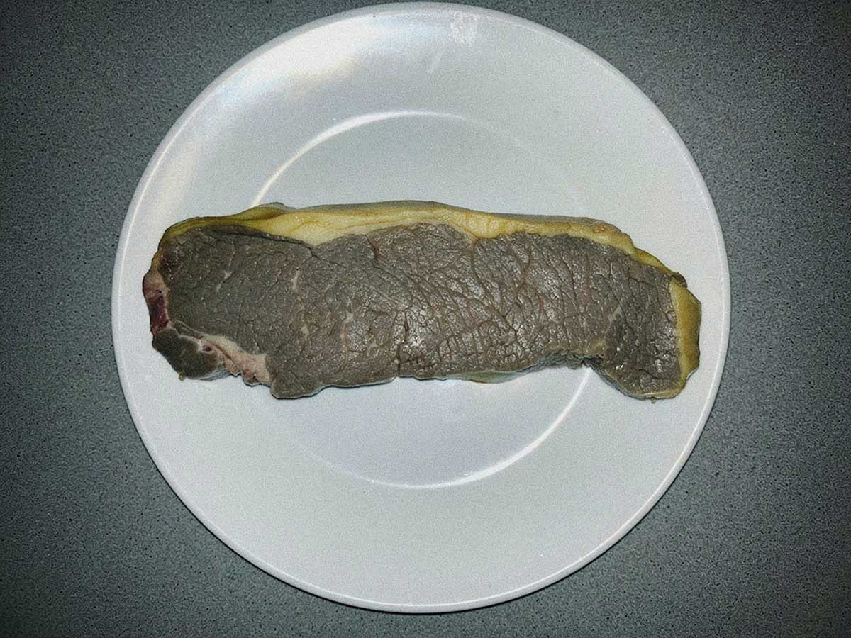 Een stuk bedorven rundvlees op een bord.
