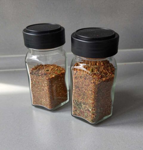 2 gedeeltelijk gevulde kruidenpotjes met daarin bolognesekruiden.