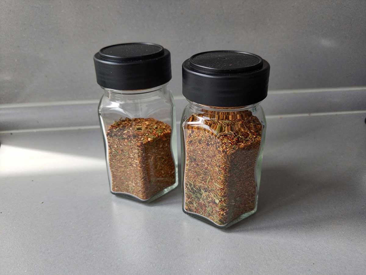 2 gedeeltelijk gevulde kruidenpotjes met daarin bolognesekruiden.