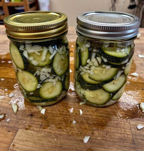 Twee inmaakpotten met daarin ingemaakte courgette met ui.