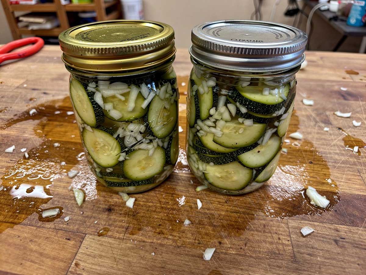 Twee inmaakpotten met daarin ingemaakte courgette met ui.