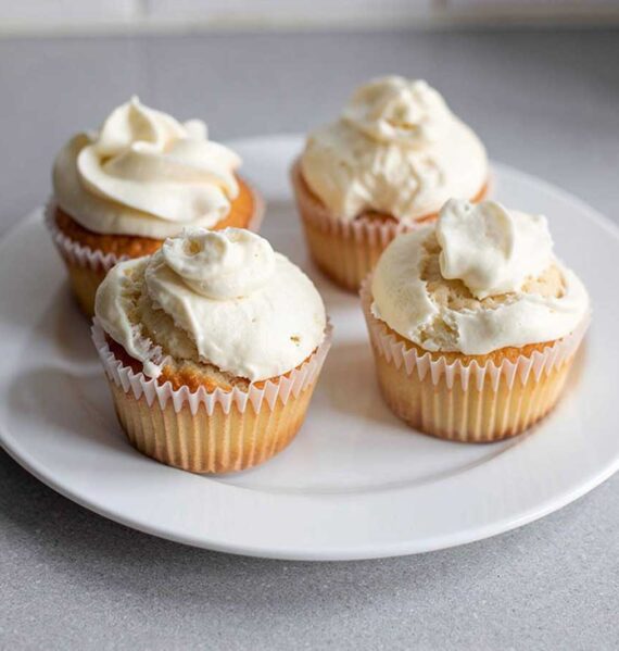 4 zelfgemaakte cupcakes met een simpele topping, op een wit bord.
