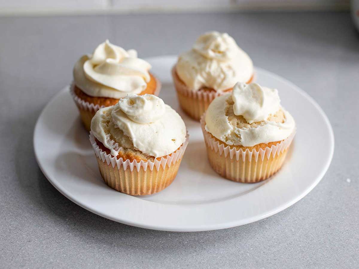 4 zelfgemaakte cupcakes met een simpele topping, op een wit bord.