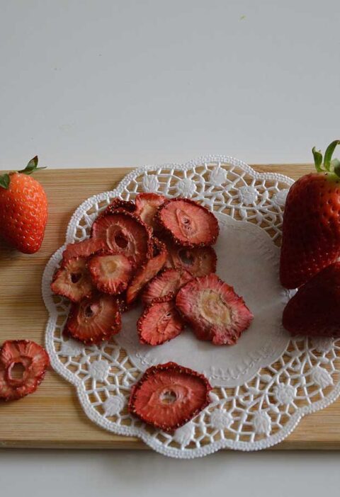 Gedroogde en verse aardbeien op een houten snijplank.