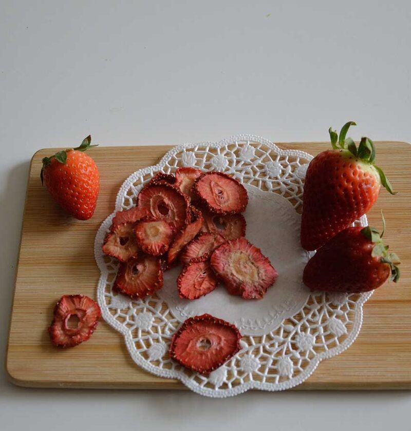 Gedroogde en verse aardbeien op een houten snijplank.