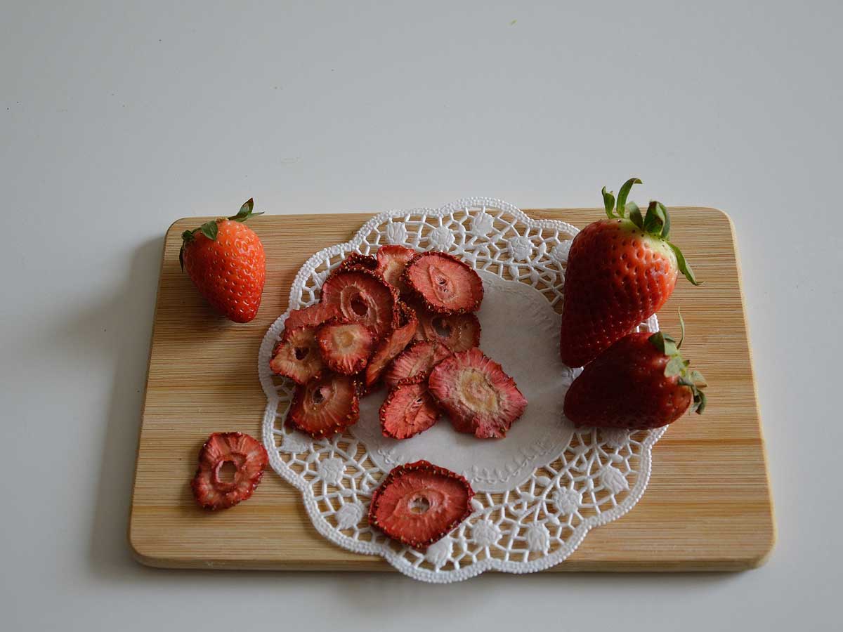 Gedroogde en verse aardbeien op een houten snijplank.