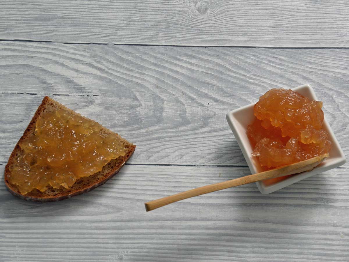 Een klein bakje vol gemberjam, en daarnaast een halve boterham met gemberjam.