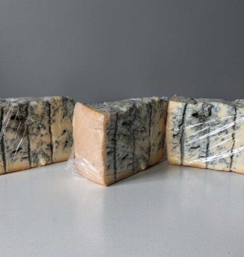 Drie stukken gorgonzola, in vershoudfolie gewikkeld.