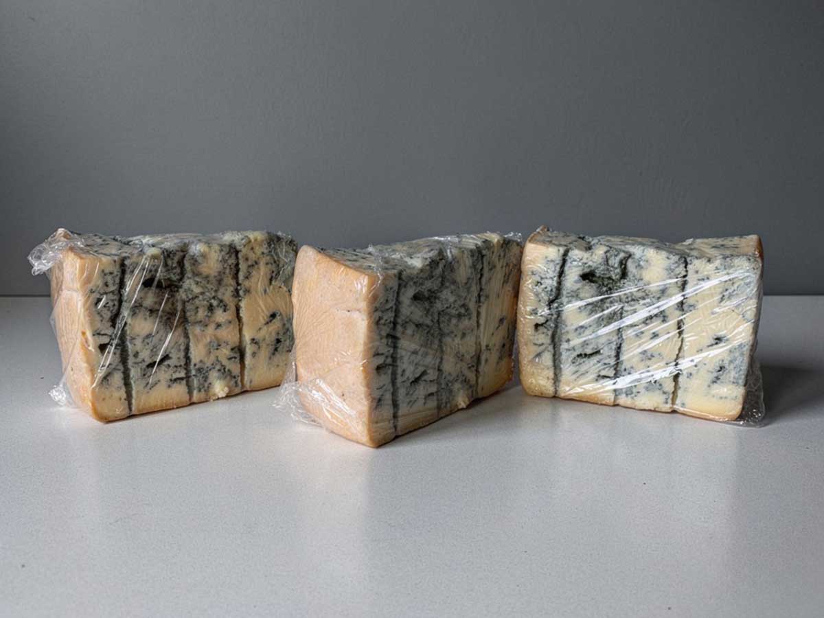Drie stukken gorgonzola, in vershoudfolie gewikkeld.