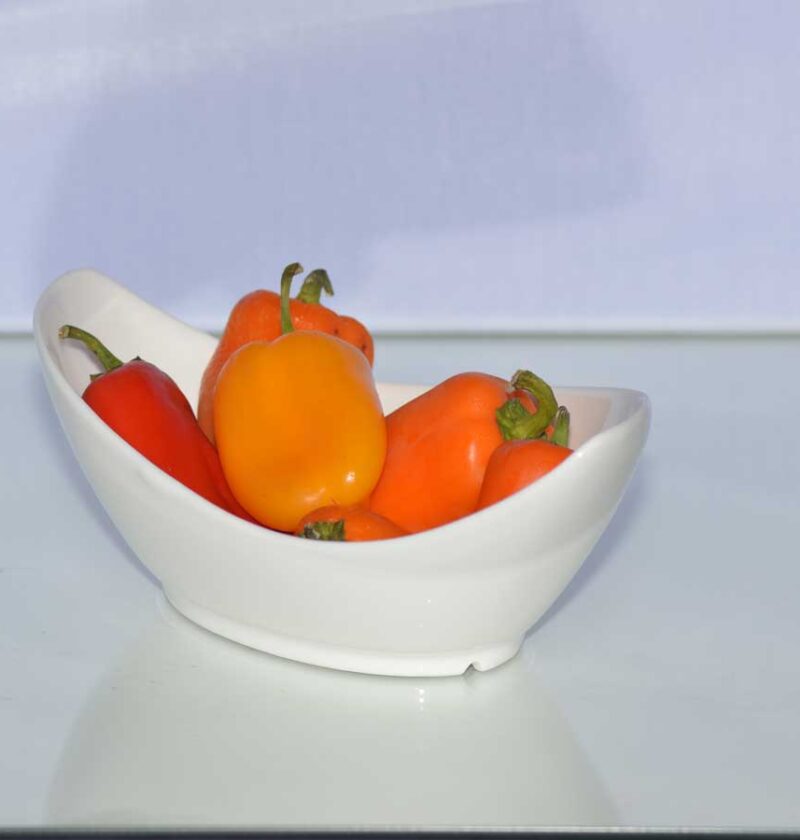 Een wit schaaltje met verse paprika, rood, geel, en oranje.