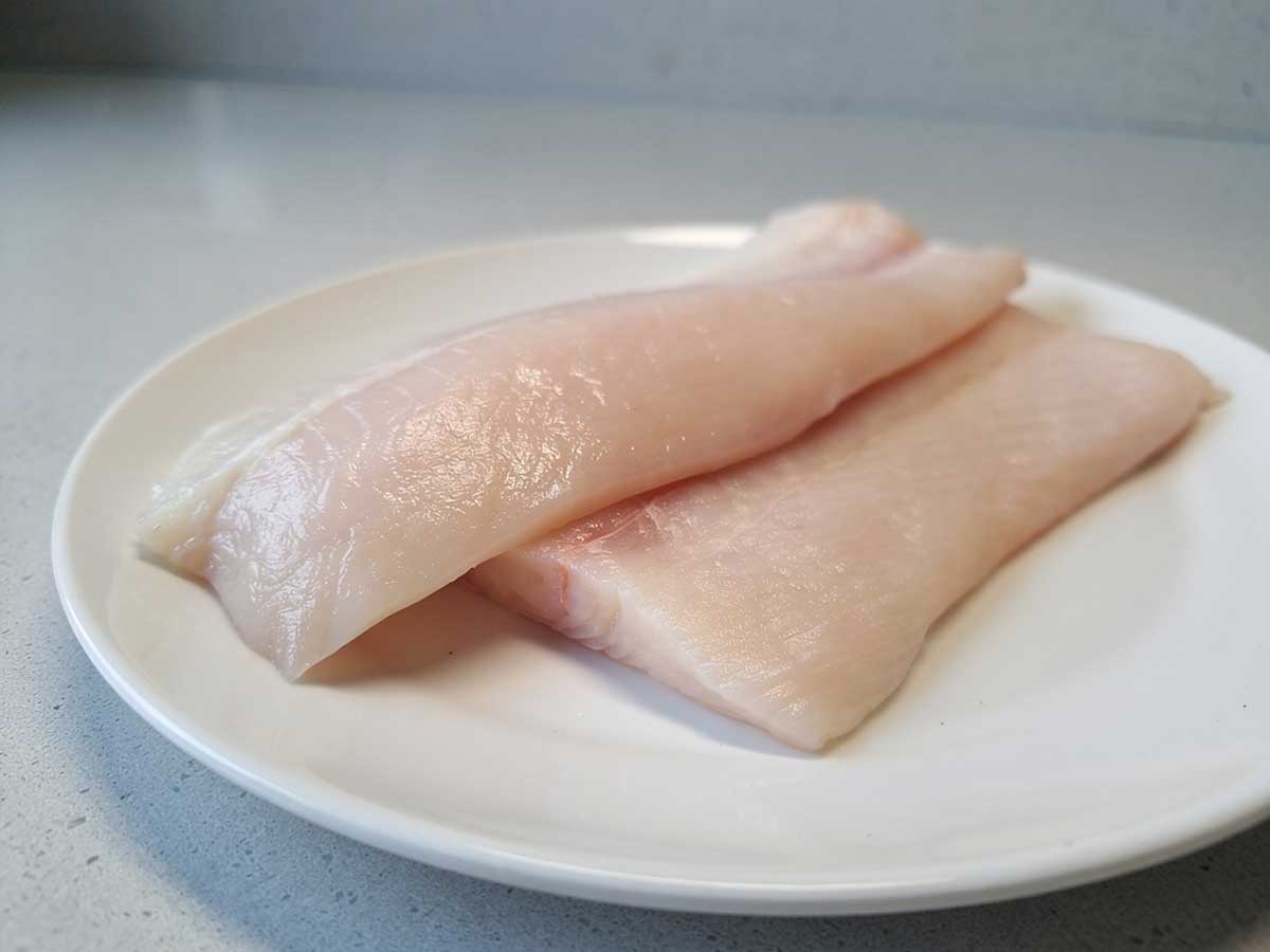 2 heilbotfilets op een wit bord, klaar om op de juiste manier bewaard te worden.