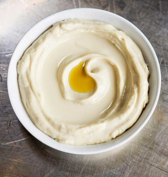 Een wit schaaltje met zelfgemaakte hummus.