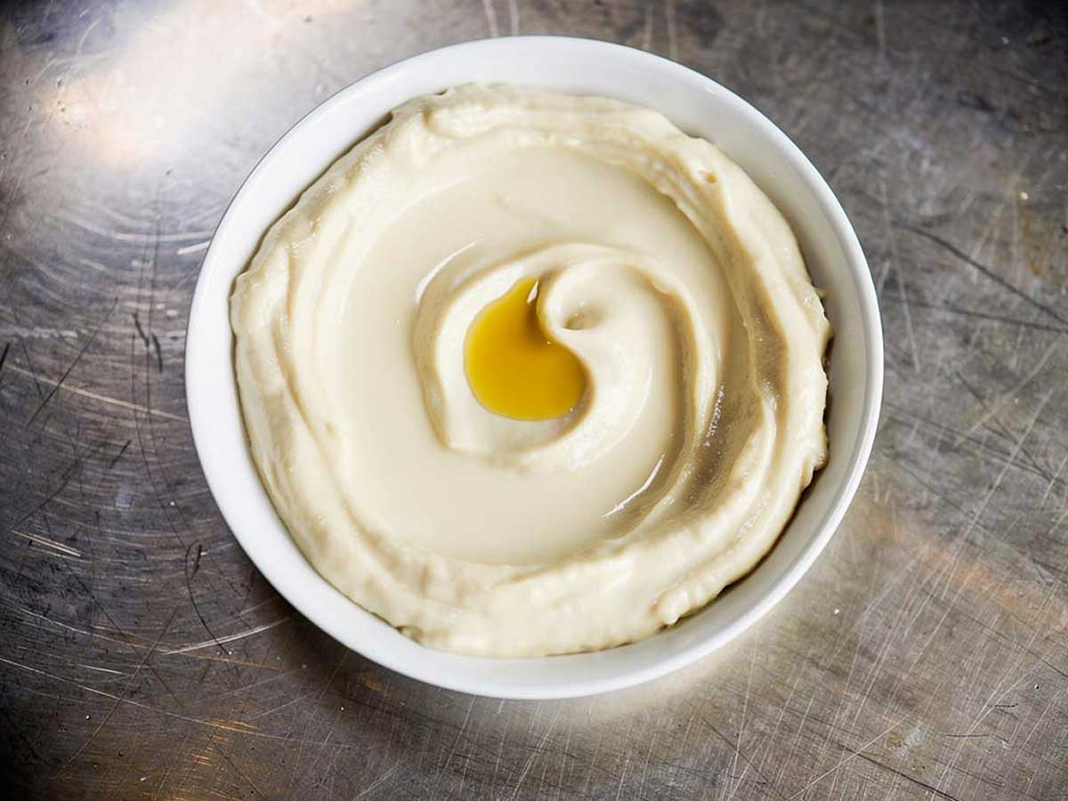 Een wit schaaltje met zelfgemaakte hummus.