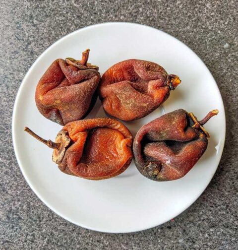 4 gedroogde hele kaki op een wit bord.