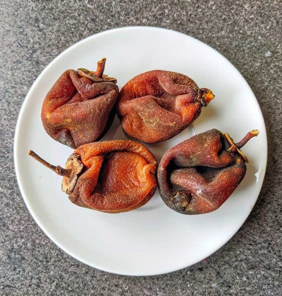 4 gedroogde hele kaki op een wit bord.
