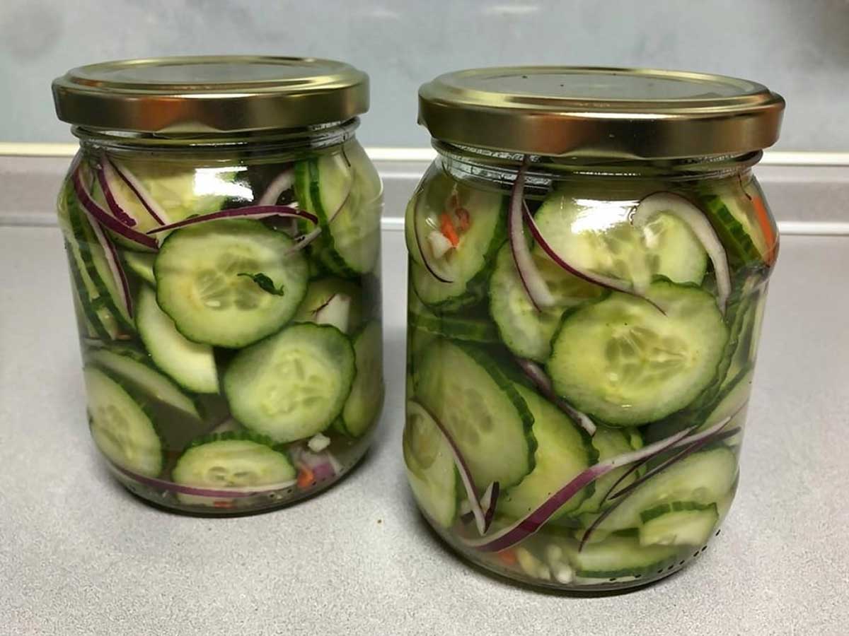 2 inmaakpotten gevuld met ingelgede kplakjes komkommer.