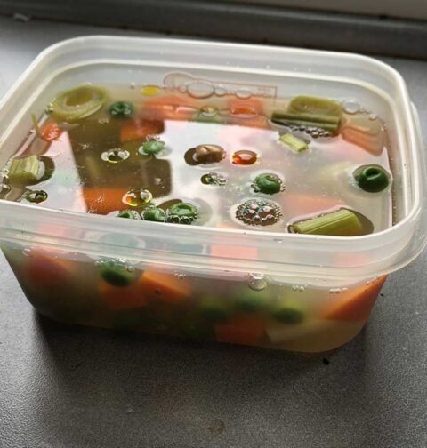 Nog warme groentesoep in een plastic bakje, open, om af te kunnen koelen.