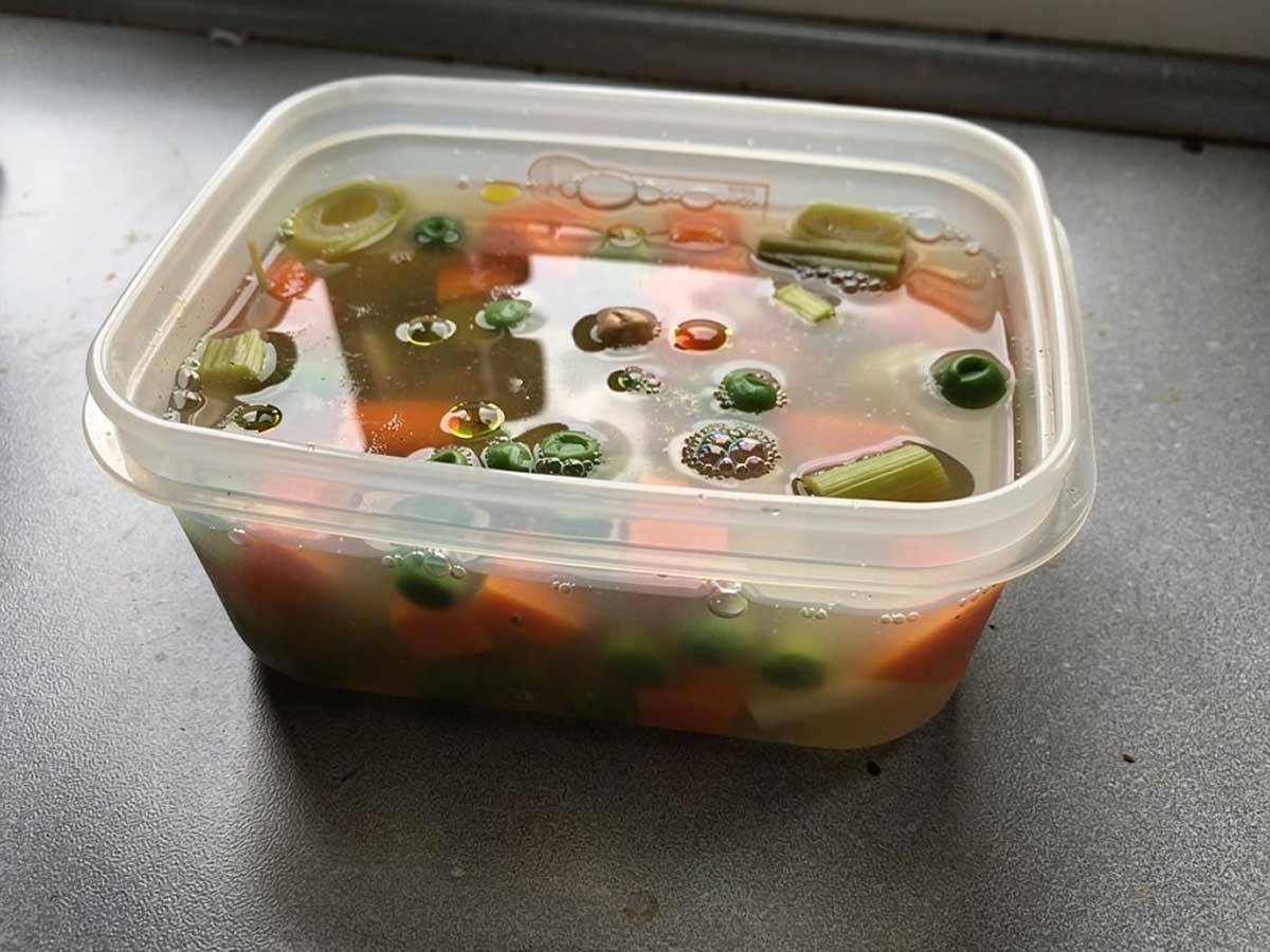Nog warme groentesoep in een plastic bakje, open, om af te kunnen koelen.