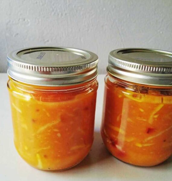 2 jampotten gevuld met zelfgemaakte mangochutney.