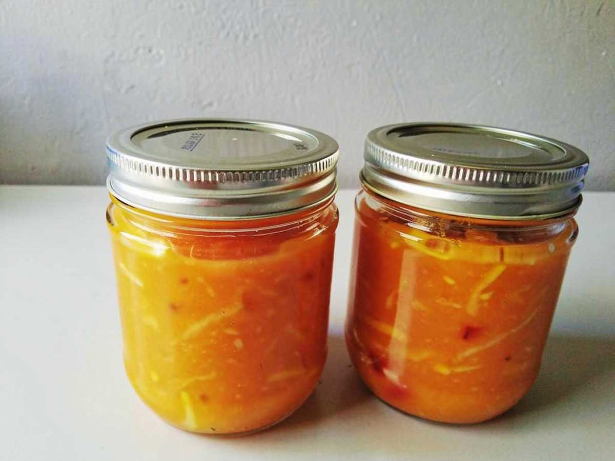 2 jampotten gevuld met zelfgemaakte mangochutney.
