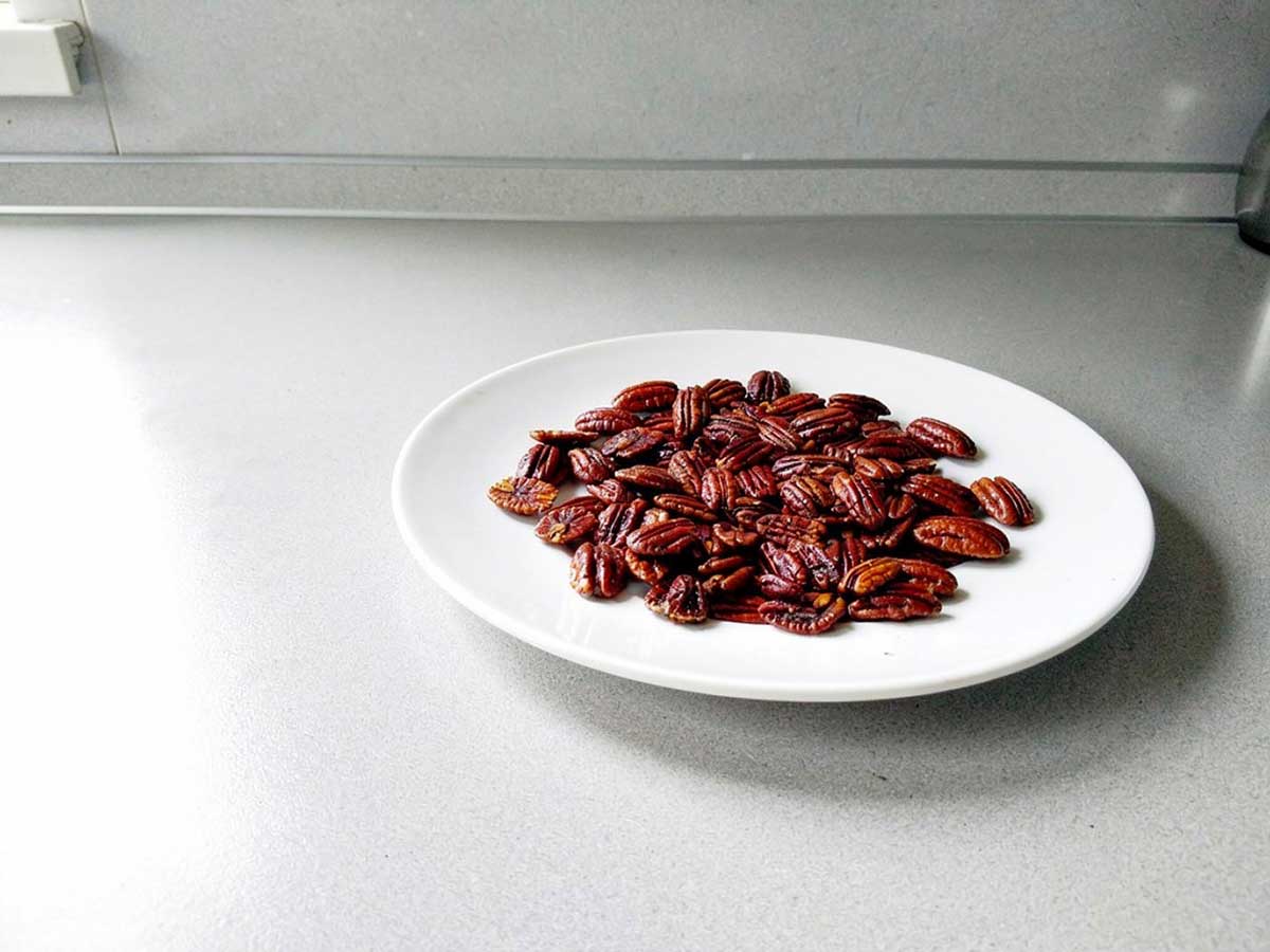 Een bordje met gekonfijte pecannoten.
