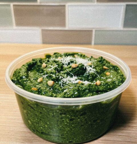 Een plastic bakje met zelfgemaakte groene pesto.