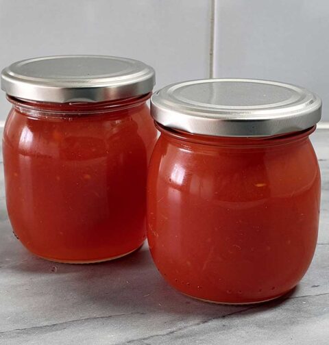 2 grote jampotten met daarin zelfgemaakte rozenboteljam.