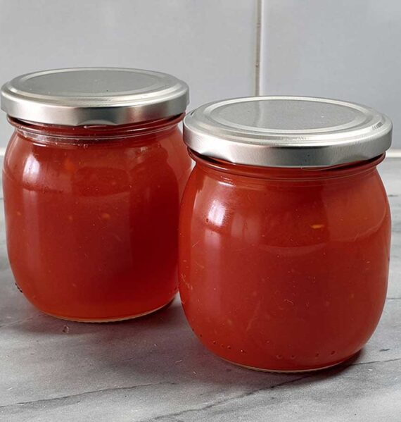 2 grote jampotten met daarin zelfgemaakte rozenboteljam.