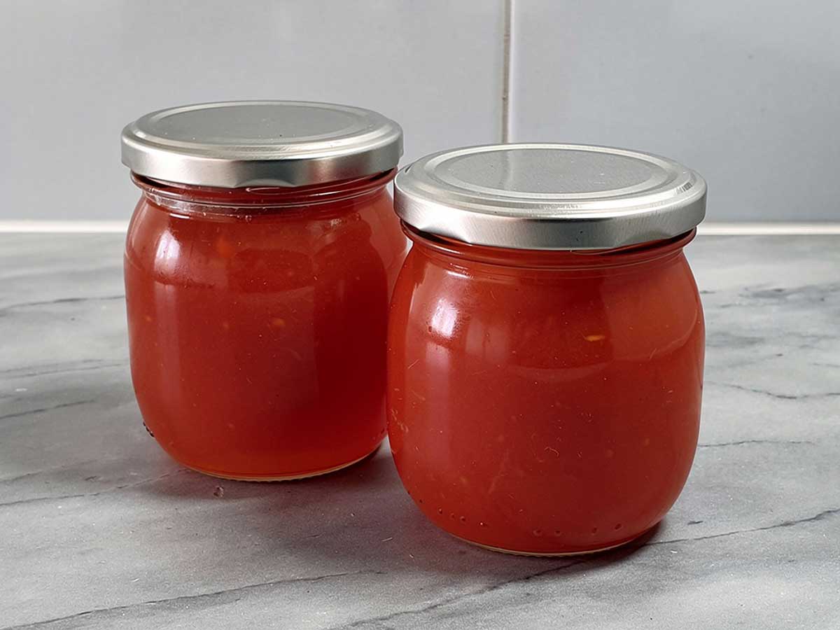 2 grote jampotten met daarin zelfgemaakte rozenboteljam.